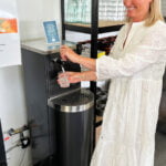 Bild på en leende person som häller upp vatten från en vattenautomat.
