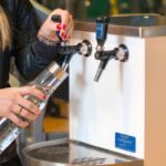 Bild på en person som häller upp vatten från en vattenautomat.