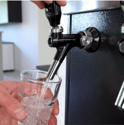 Glas som fylls på med kolsyrat vatten från Water Companys Tower vattenautomat.