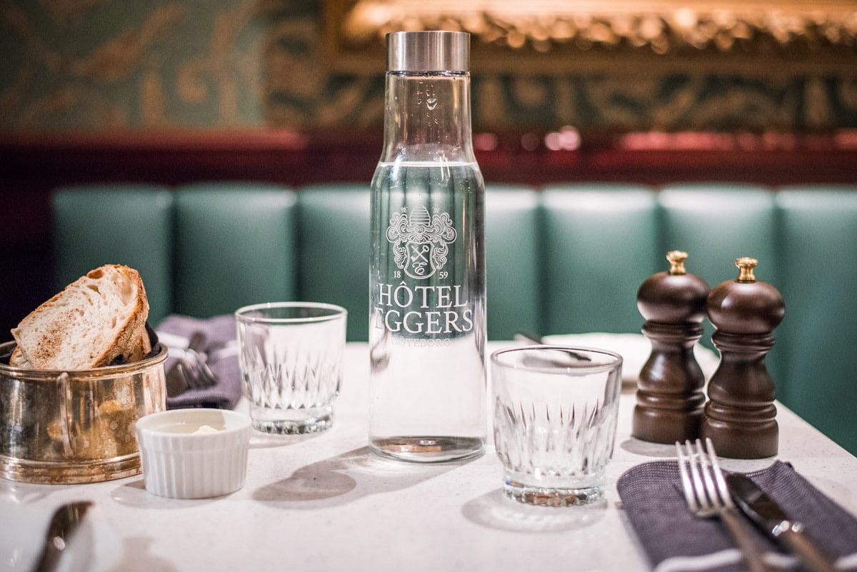 En bild av en graverad vattenkaraff i glas som står på ett restaurangbord.